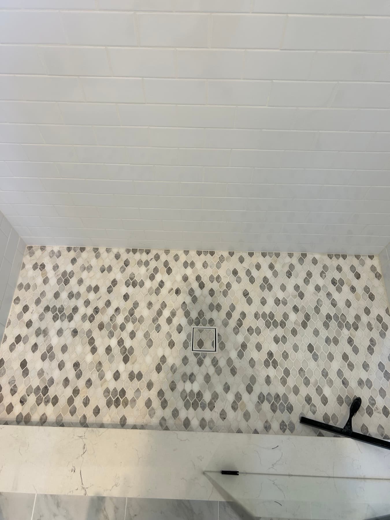 Marble shower with pebble mosaic accent